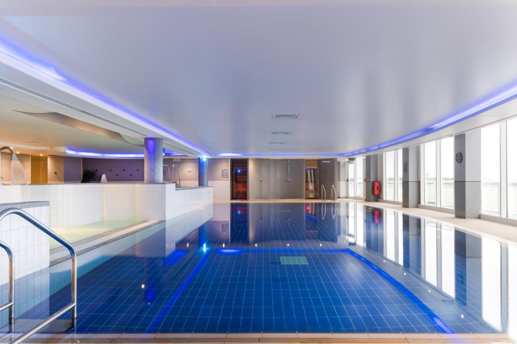 Voco St. David'S Cardiff By Ihg Hotel Buitenkant foto The photo shows an indoor swimming pool area. The pool features blue tile flooring and illuminated edges with soft lighting that creates a calming atmosphere. There are modern design elements, including walls that are primarily pale and a ceiling tha